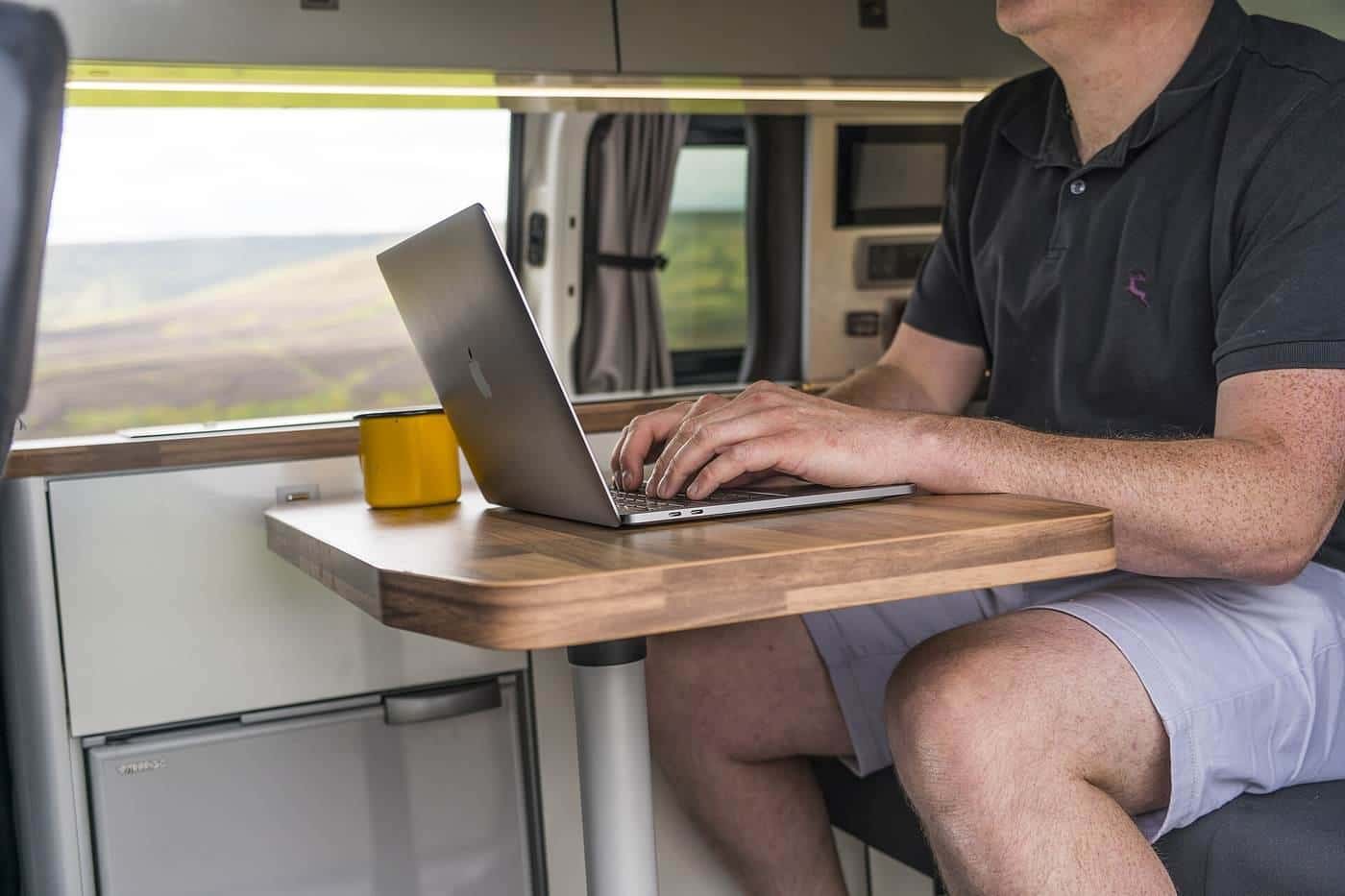 A man working on a laptop at a table inside a campervan