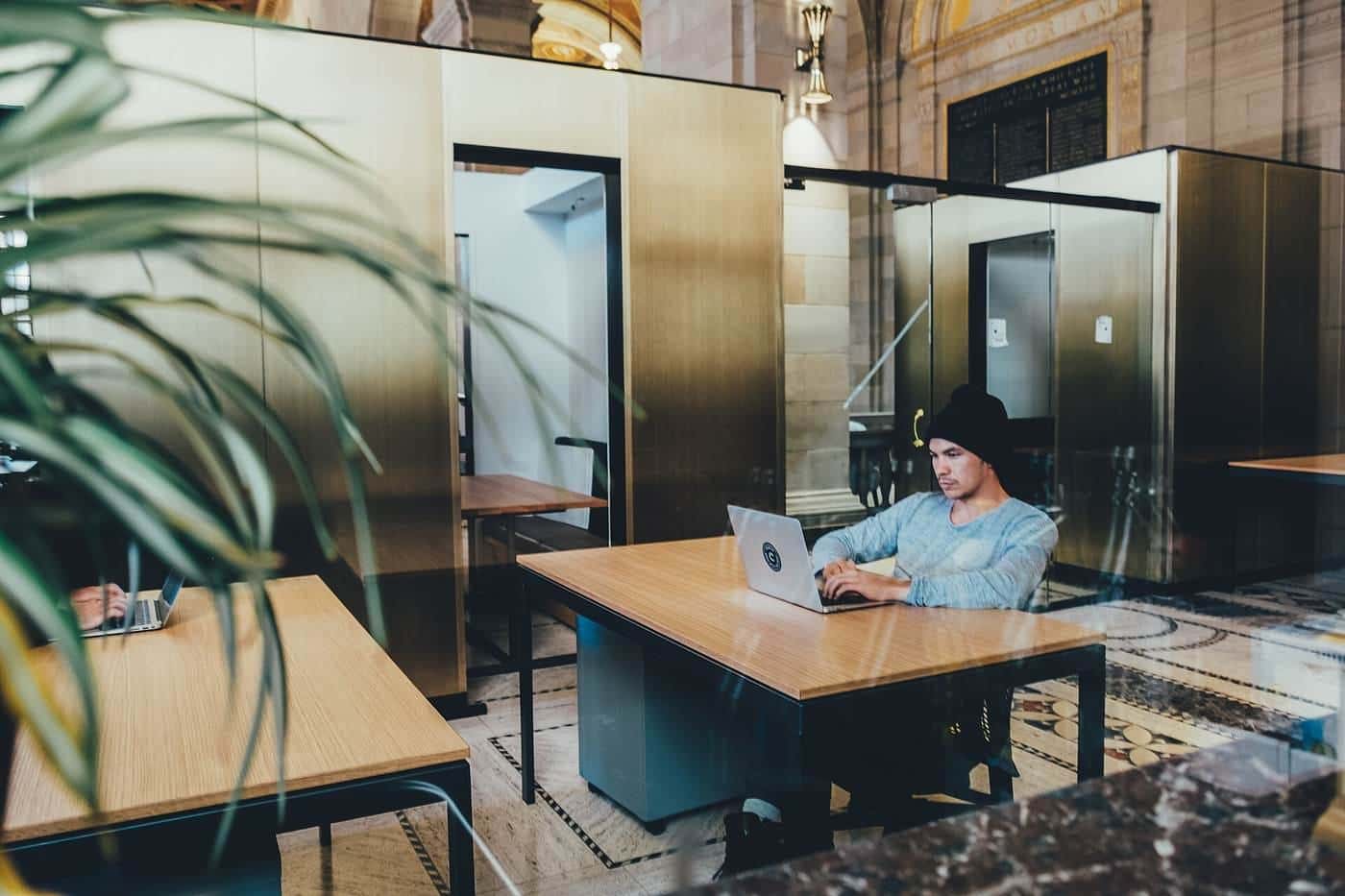 A person working at a laptop at a large desk in a bright room