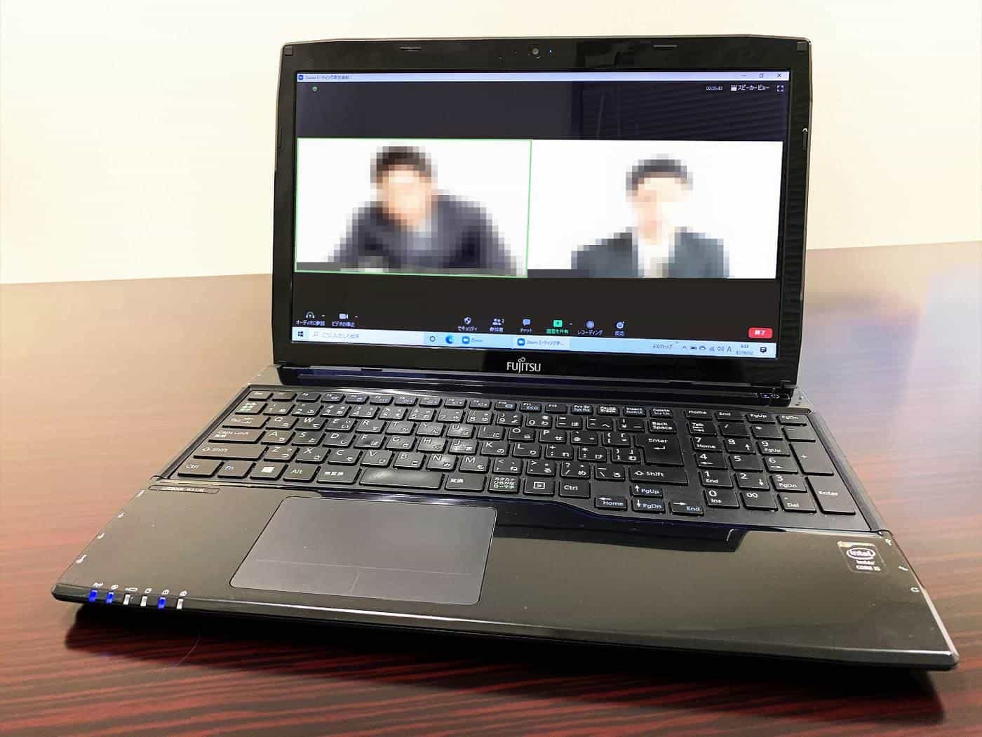A laptop on a desk showing a video call with two people